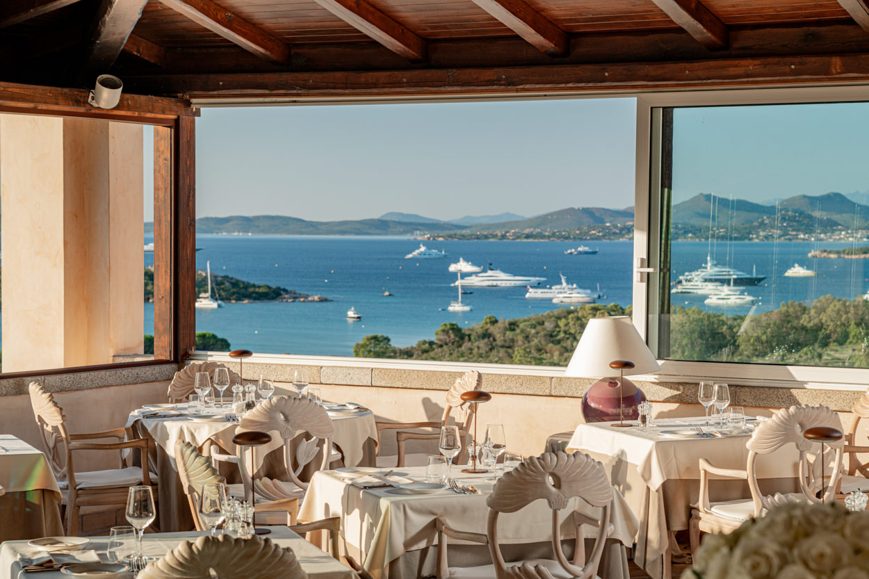 Veranda vista mare del ristorante in hotel, illuminata per la cena, catturata da un fotografo specializzato in hotel a Porto Cervo. Immagine che mostra l'atmosfera elegante e accogliente dell'area pranzo con vista panoramica sul mare.
