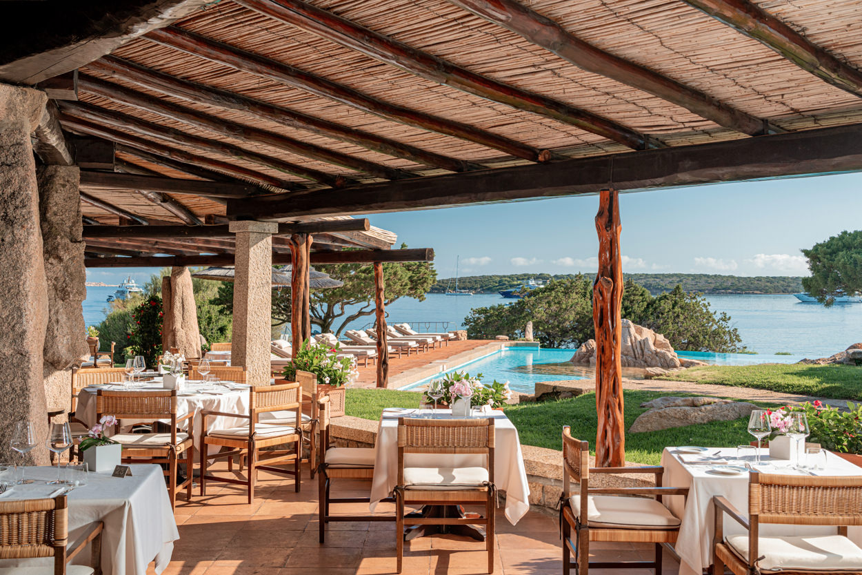 Terrazza dell'hotel Pitrizza, 5 stelle, con apparecchiatura da colazione e vista su piscina e mare. Immagine che evidenzia l'eleganza e la qualità del servizio in un contesto esclusivo.