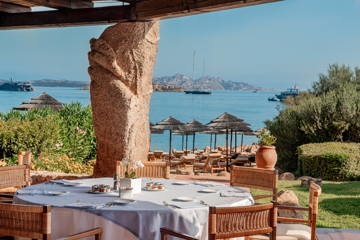 Vista della terrazza dell'hotel Pitrizza sulla Costa Smeralda, con tavolo imbandito per colazione e vista mare. Immagine scattata al mattino con luce soffusa, da un fotografo specializzato in hotel nella Costa Smeralda.