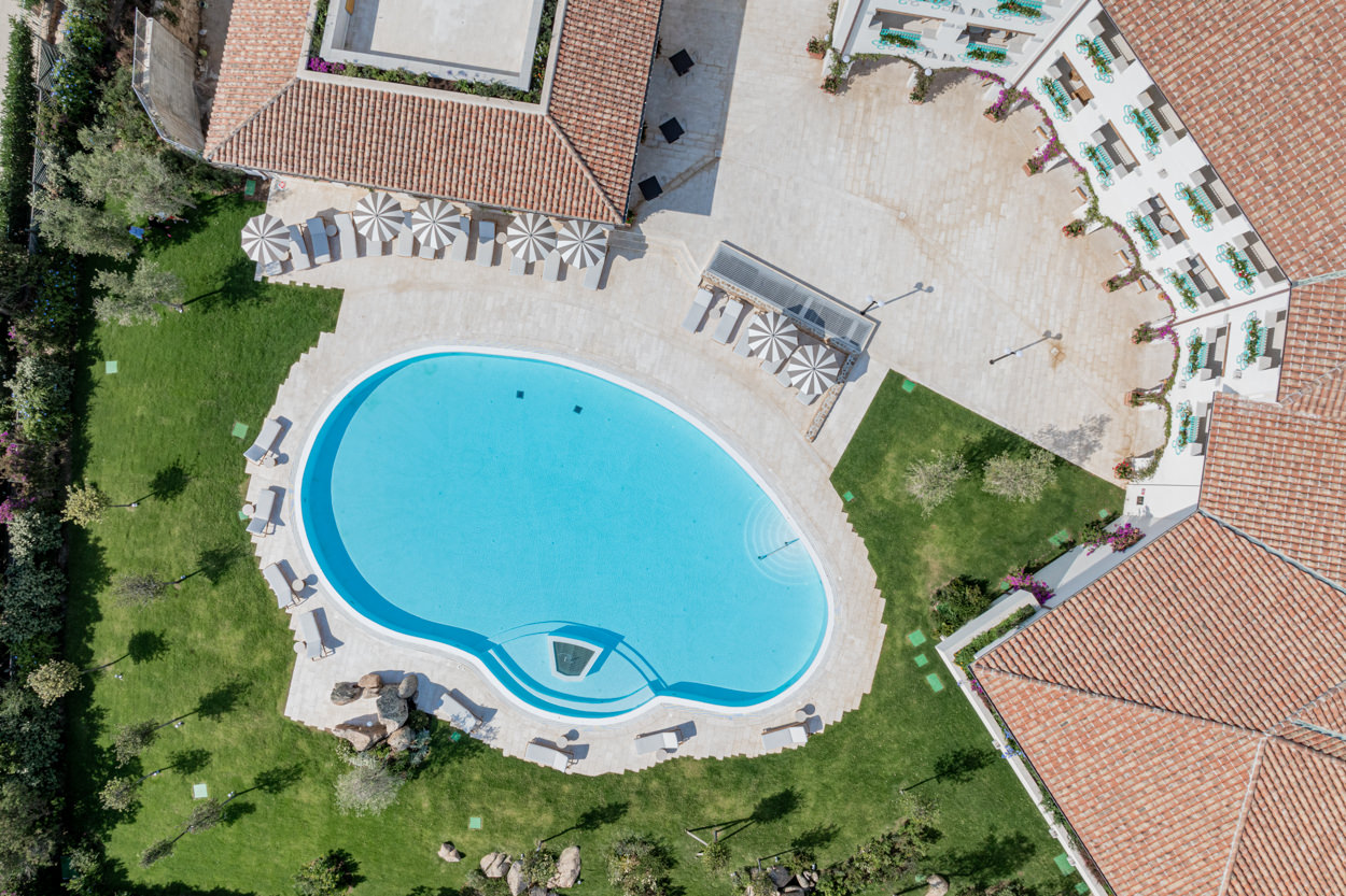 Vista aerea della piscina di un hotel, catturata da un drone. Foto realizzata da un fotografo specializzato in hotel, evidenziando la posizione e il design della piscina.